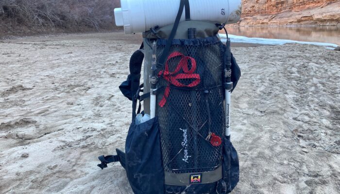 A medium shot of the waymark gear company Lite 50L on a riverbank, loaded down with gear.