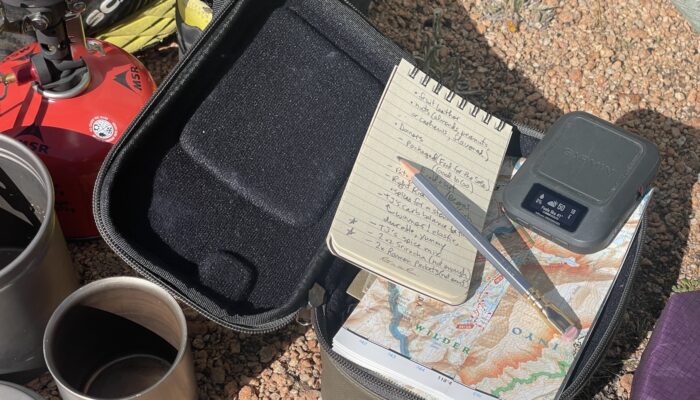 satellite messenger with notebook, pencil, coffee, map, and stove